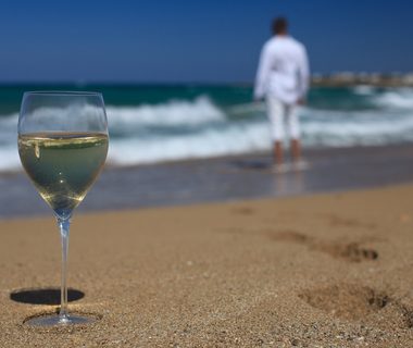 glass of wine, and men's footprints on the beach closeup. horizontal